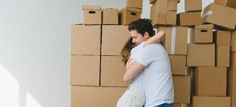 Person hugging a child in front of stacked cardboard moving boxes