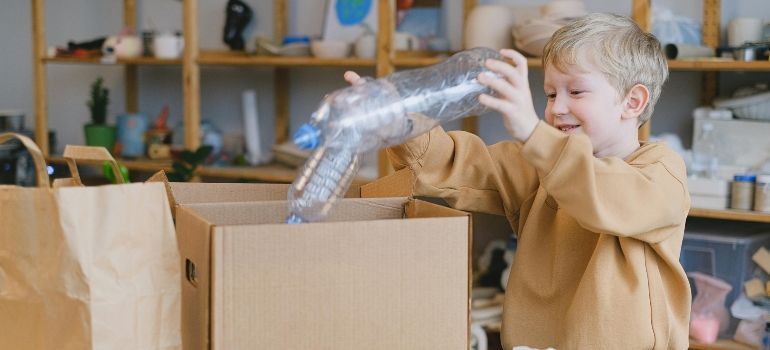 Child playing with a silver robot toy at a cardboard box in a cozy room