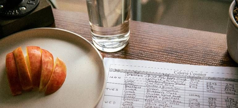 Croissant on a plate beside a glass of water and a printed form on a table