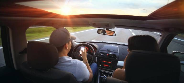 Driver and passenger in a car at sunset, looking out over an open road