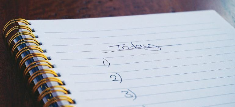 Spiral notebook page titled “Tasks” with a handwritten numbered list on a wooden table