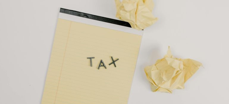 Yellow notepad labeled “TAX” with crumpled papers on a light background