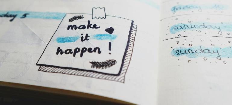 Notebook page with a sticky note reading “make it happen!” and a small heart icon.