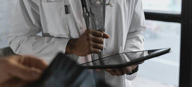 Doctor holding a tablet and using a stylus in a bright clinical setting