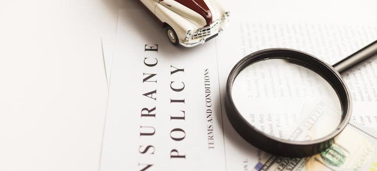 Magnifying glass over insurance policy document with pen on white desk