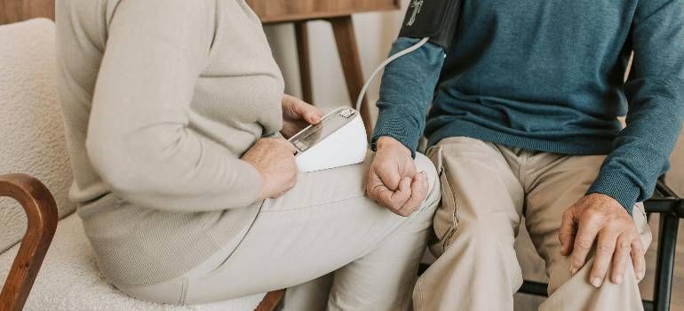 Two people sitting close together on a couch, holding hands in a calm indoor setting.
