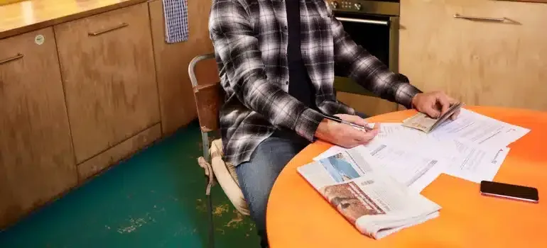 Person sorting papers at an orange table in a wood-paneled room