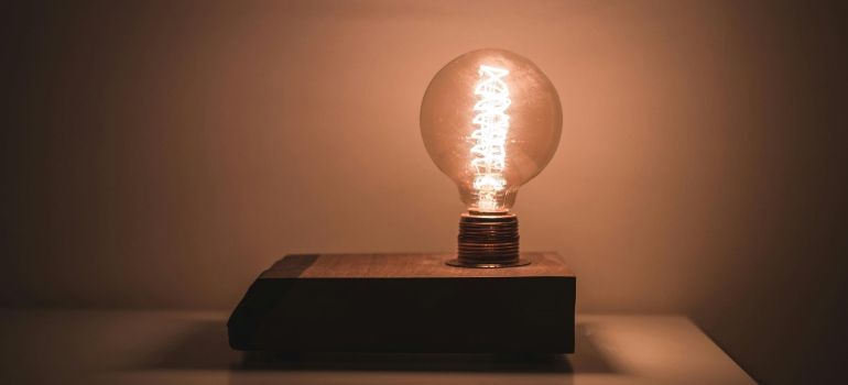 A glowing light bulb on a black base against a warm brown background
