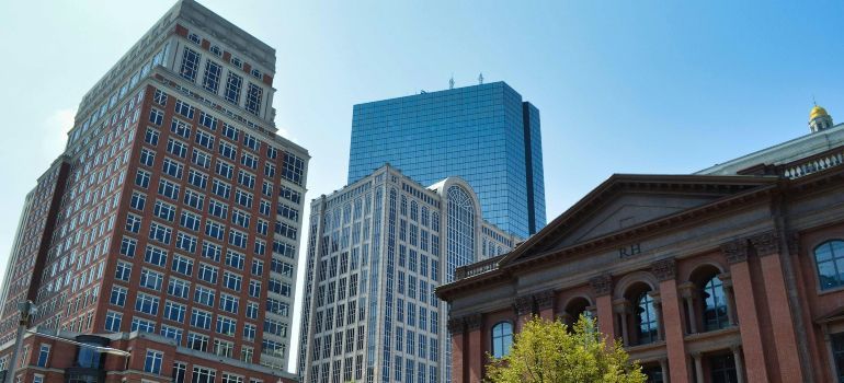 Downtown skyline with brick and glass buildings beside a historic red-brick structure under a clear blue sky