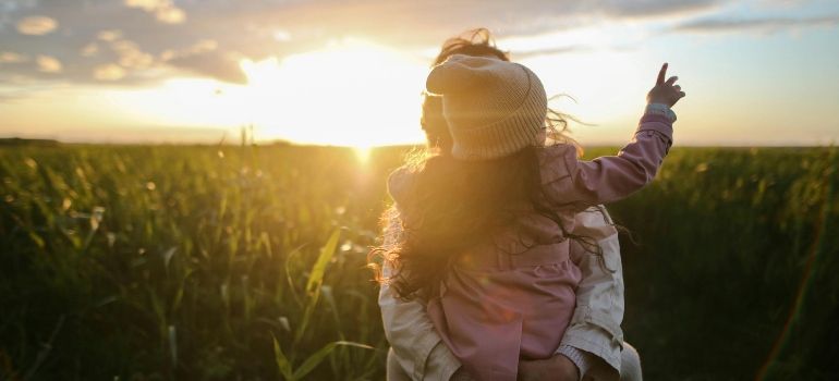 Person with raised arm in a sunlit field at sunset