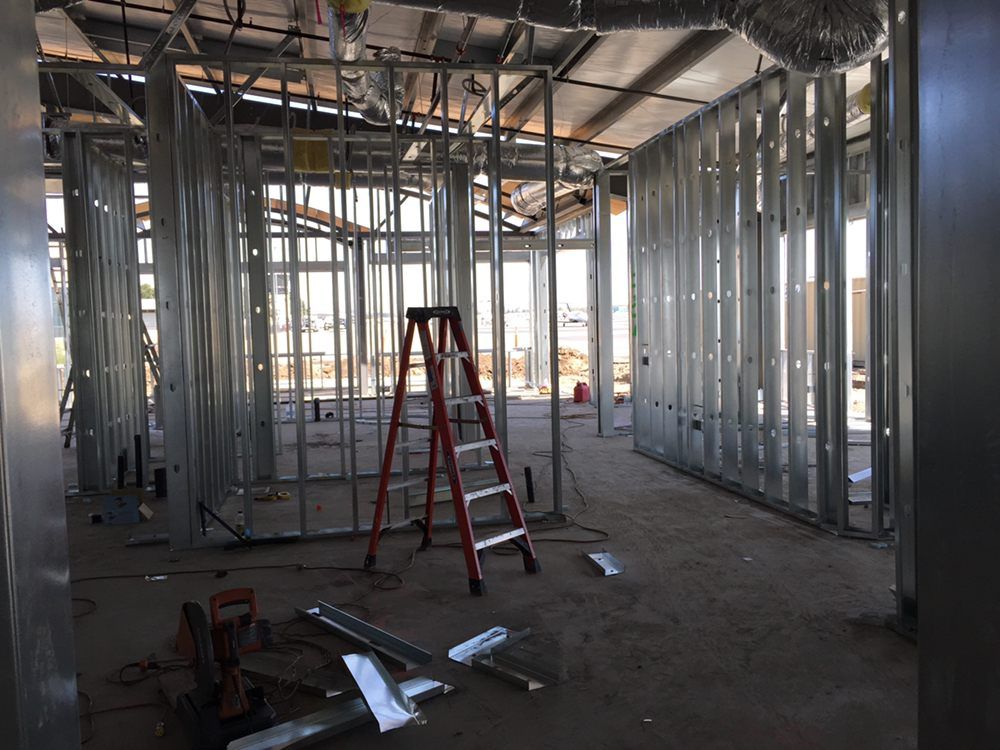 Interior metal stud framing of a building under construction; red ladder in the center.
