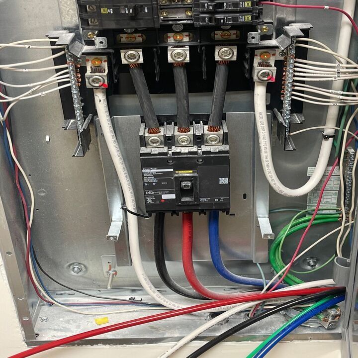 Electrical panel with wires connected to breakers, red, blue, black, white and green wires visible.