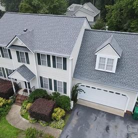 A high-angle view of a two-story suburban home with grey shingles.