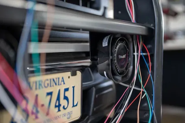 Close-up of a vehicle's front grill with a Virginia license plate, wiring, and a cooling fan.