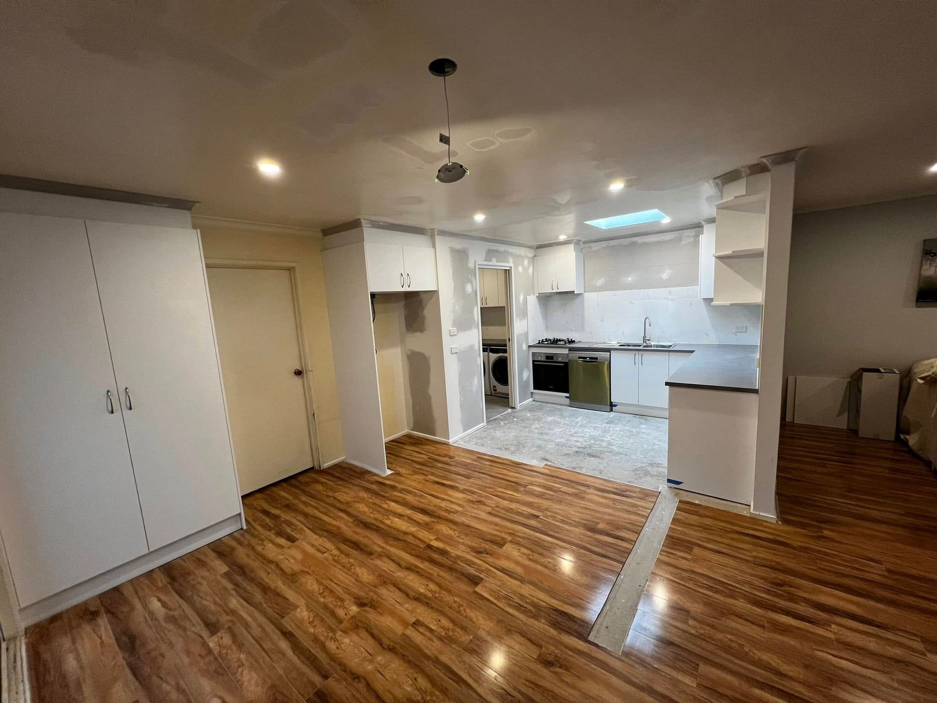 A Living Room with Hardwood Floors and A Kitchen in The Background — P & M Maintenance Building Services in Yass River, NSW
