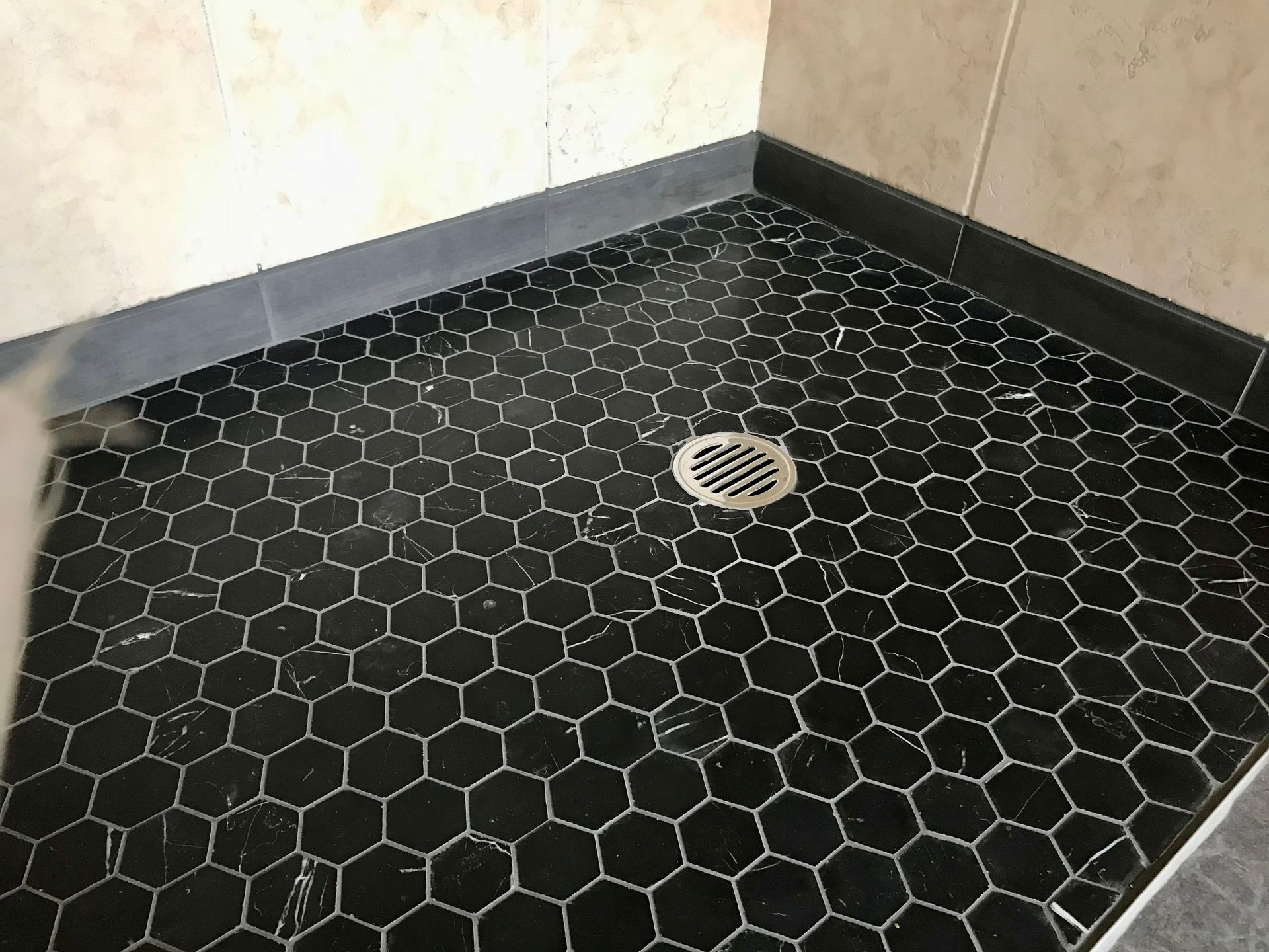 A Shower Stall with Black Tiles and A Drain — P & M Maintenance Building Services in Yass River, NSW