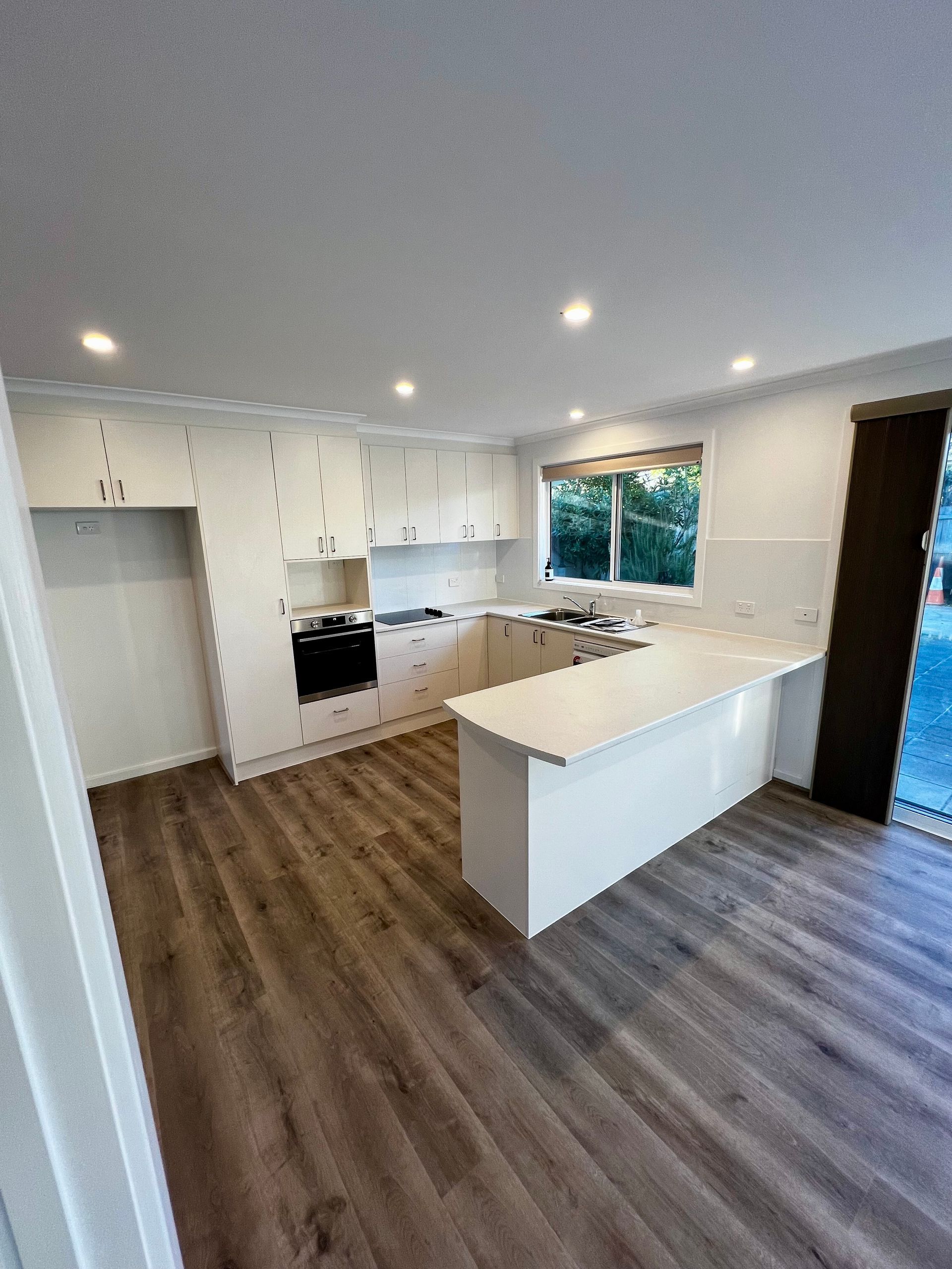 A Kitchen with White Cabinets and A Wooden Floor — P & M Maintenance Building Services in Yass River, NSW