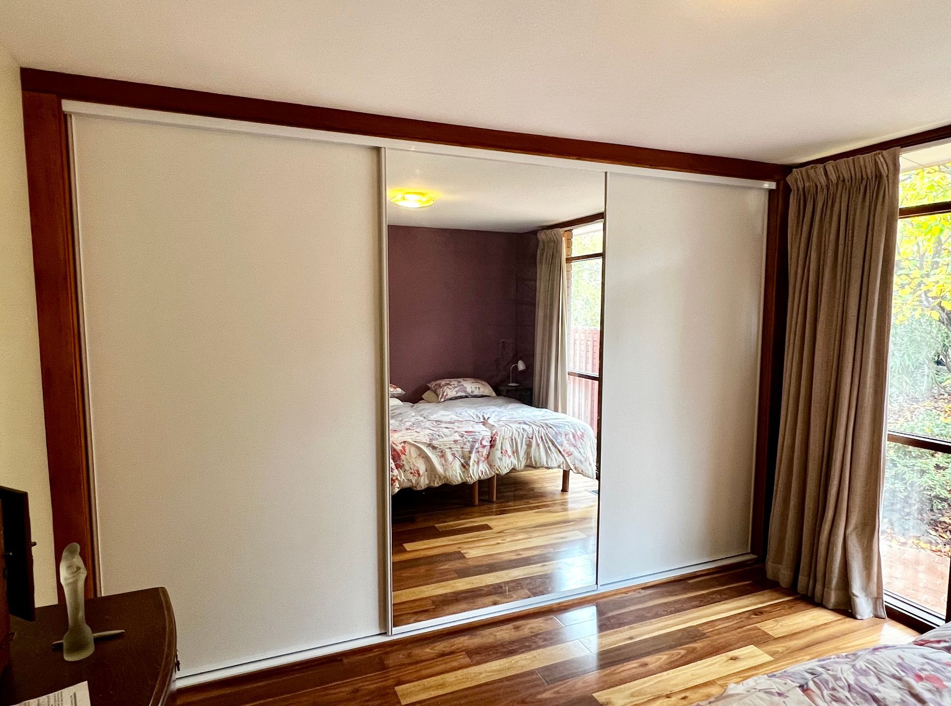 A Bedroom with Sliding Glass Doors and A Large Mirror — P & M Maintenance Building Services in Yass, NSW