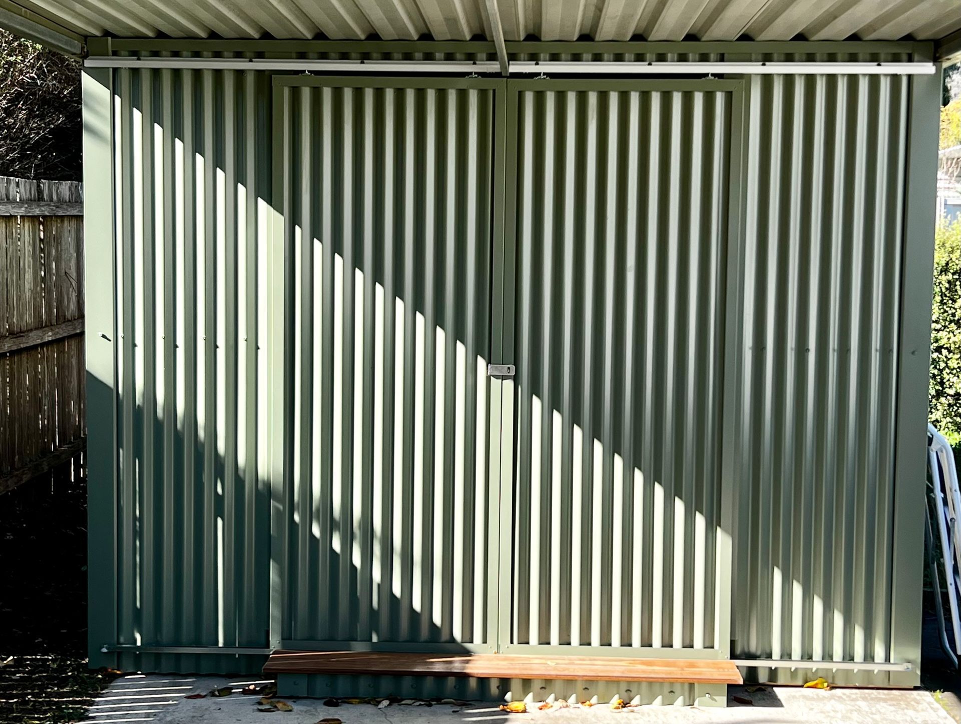 A Green Shed with A Wooden Bench Underneath It — P & M Maintenance Building Services in Murrumbateman, NSW