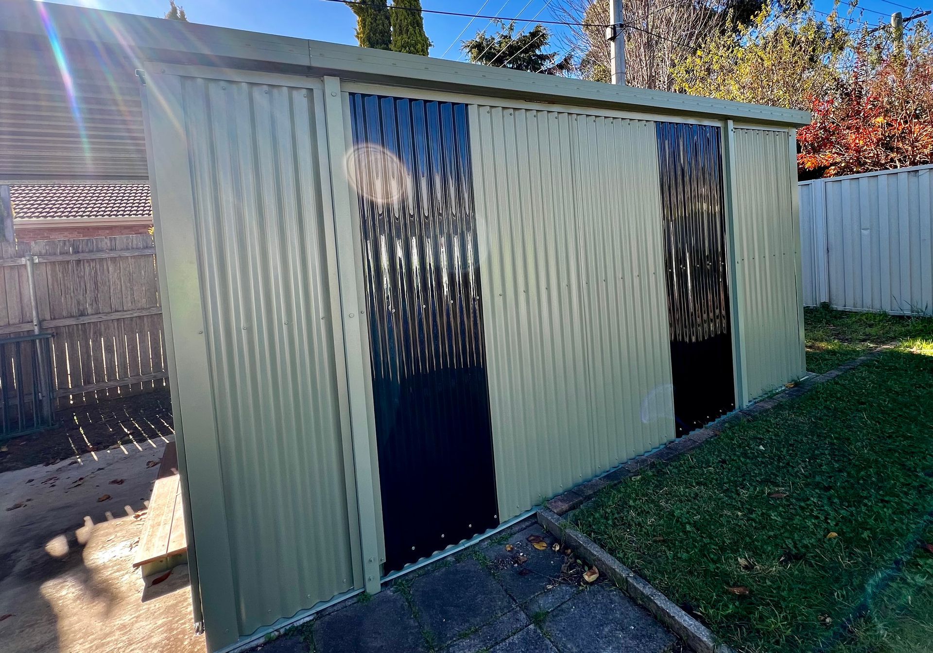 A Shed with Two Doors Painted Black and White in A Backyard — P & M Maintenance Building Services in Murrumbateman, NSW