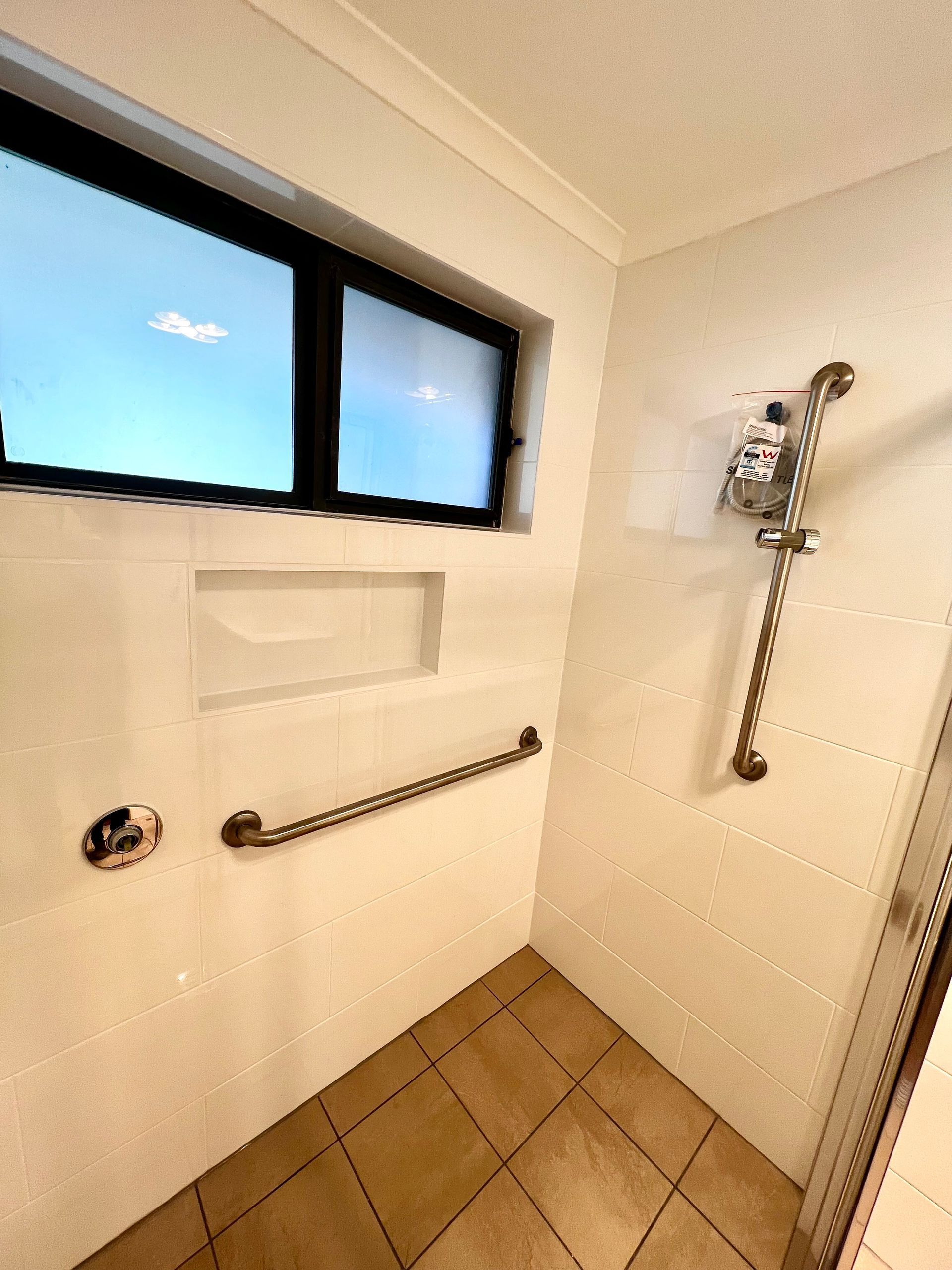 A Shower With Handrails And A Window — P & M Maintenance Building Services in Yass River, NSW