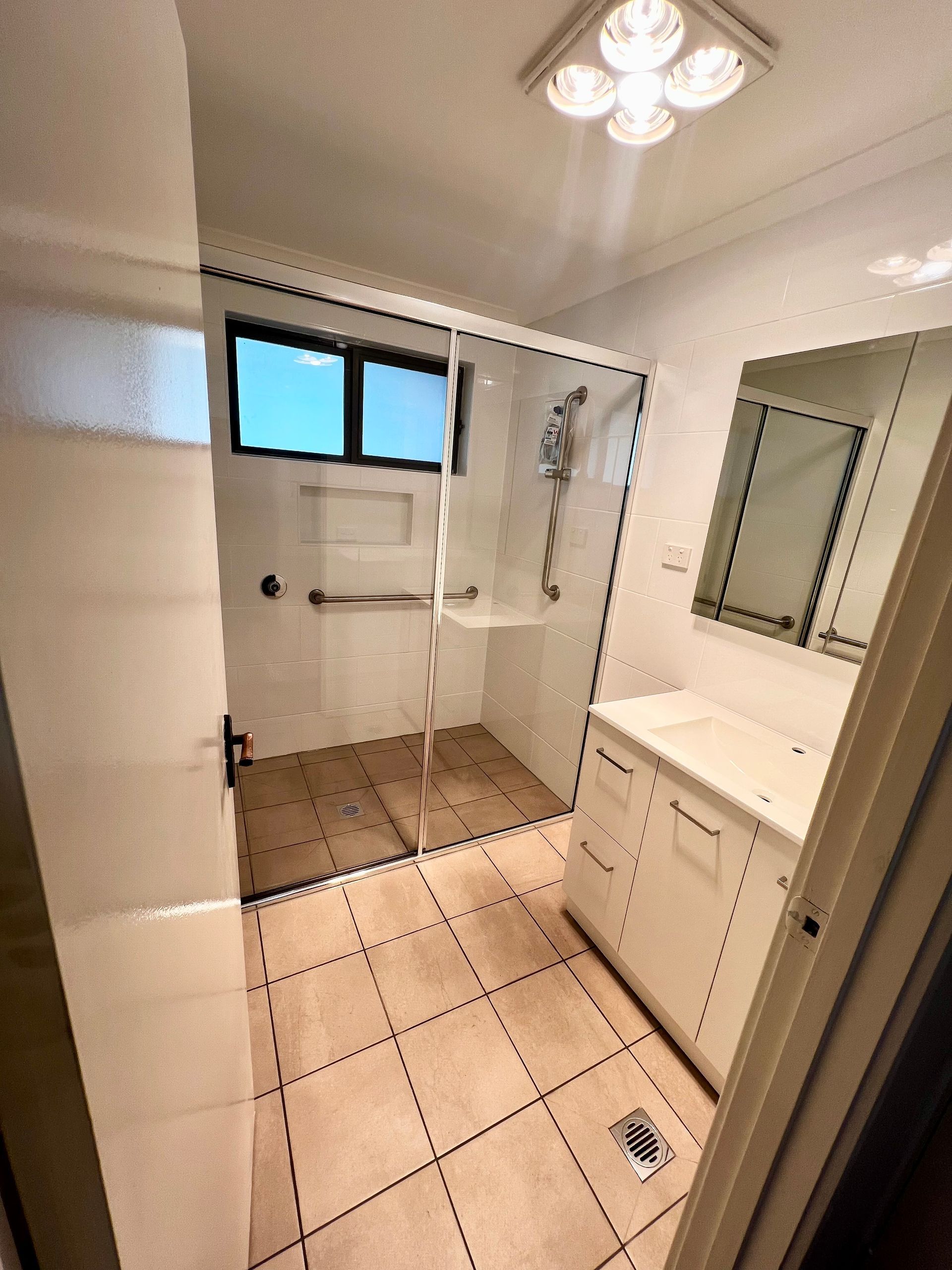 A Bathroom with A Shower , Sink and Mirror — P & M Maintenance Building Services in Yass River, NSW