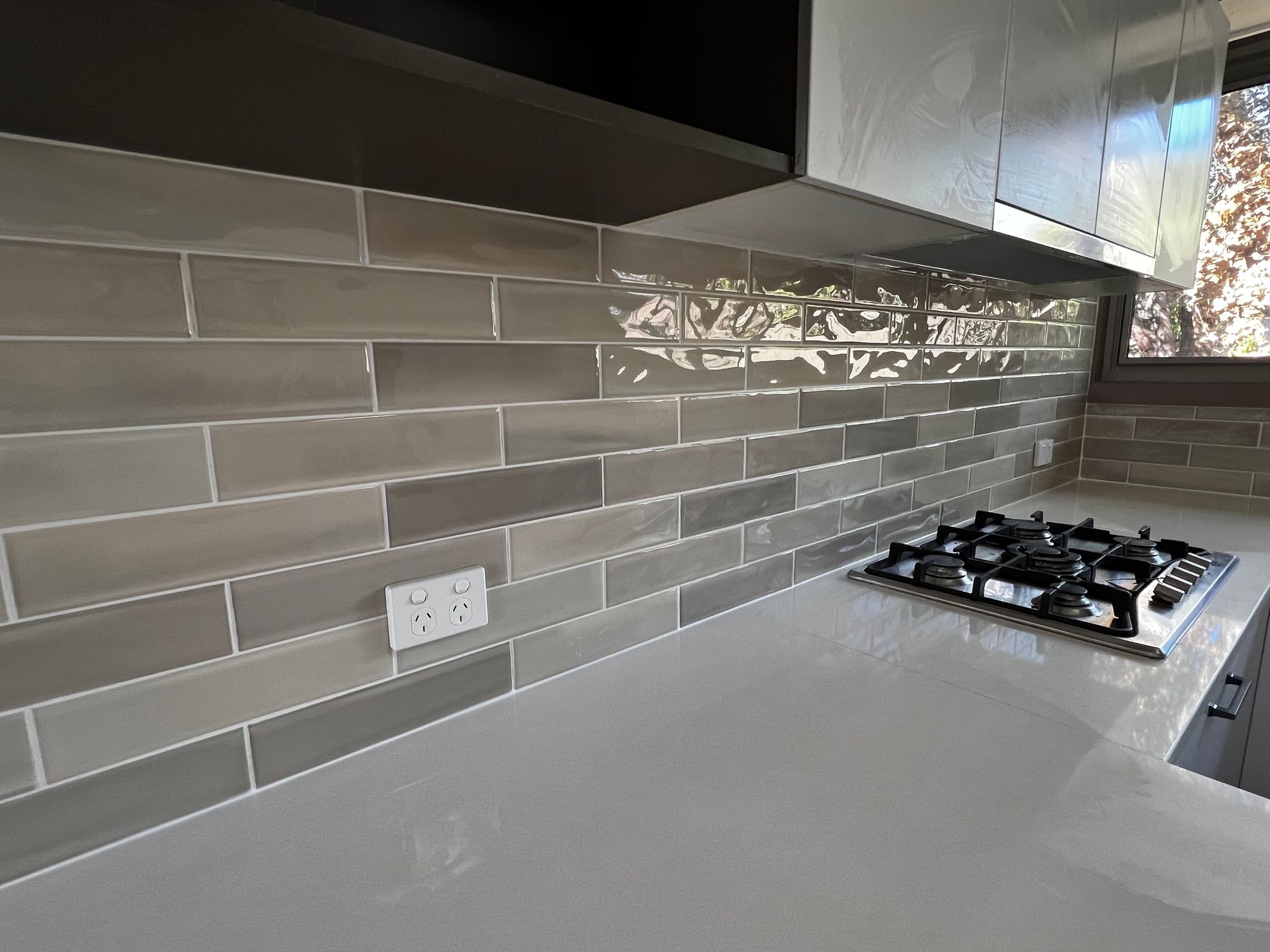 A Kitchen with A Stove Top Oven and A Gray Tile Backsplash — P & M Maintenance Building Services in Gungahlin, ACT