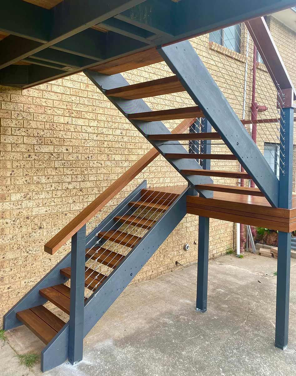 A Set of Wooden Stairs Leading up To a Brick Building — P & M Maintenance Building Services in Belconnen, ACT
