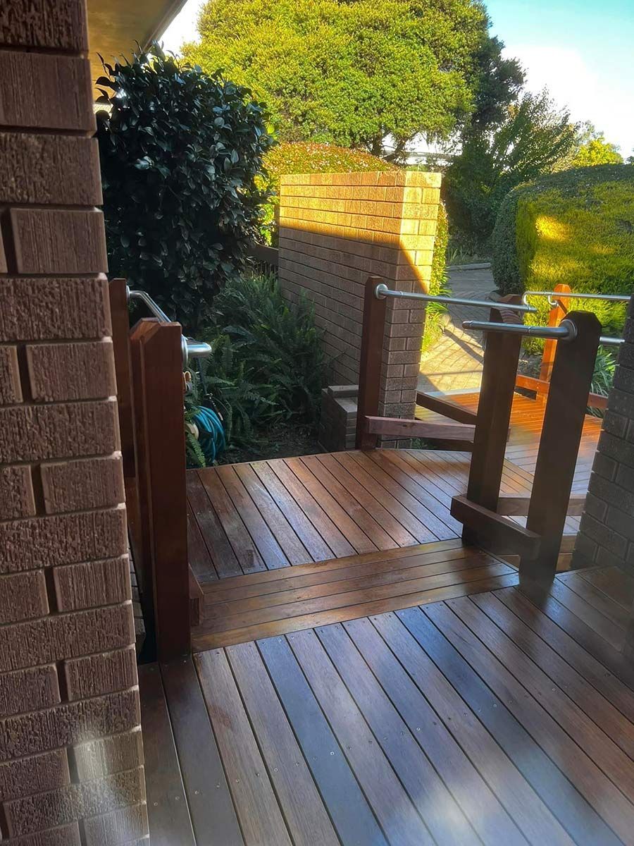 A Wooden Deck with A Brick Wall in The Background — P & M Maintenance Building Services in Yass, NSW