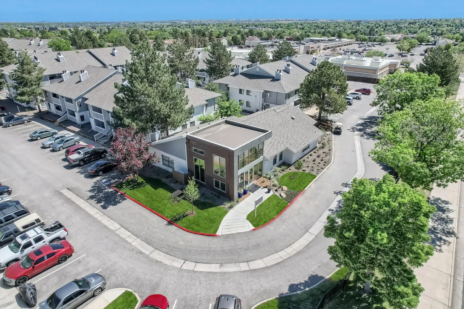Aerial view of apartment buildings and a modern clubhouse with ample parking.