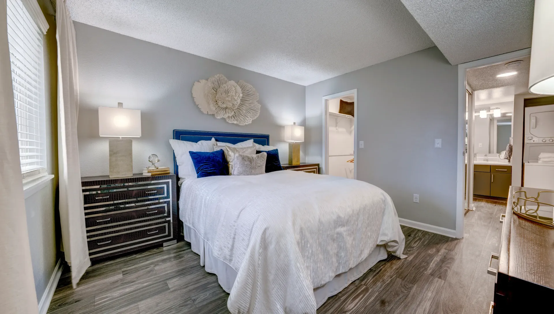 A beautifully staged bedroom with a queen-size bed, nightstands, a dresser, and a walk-in closet.