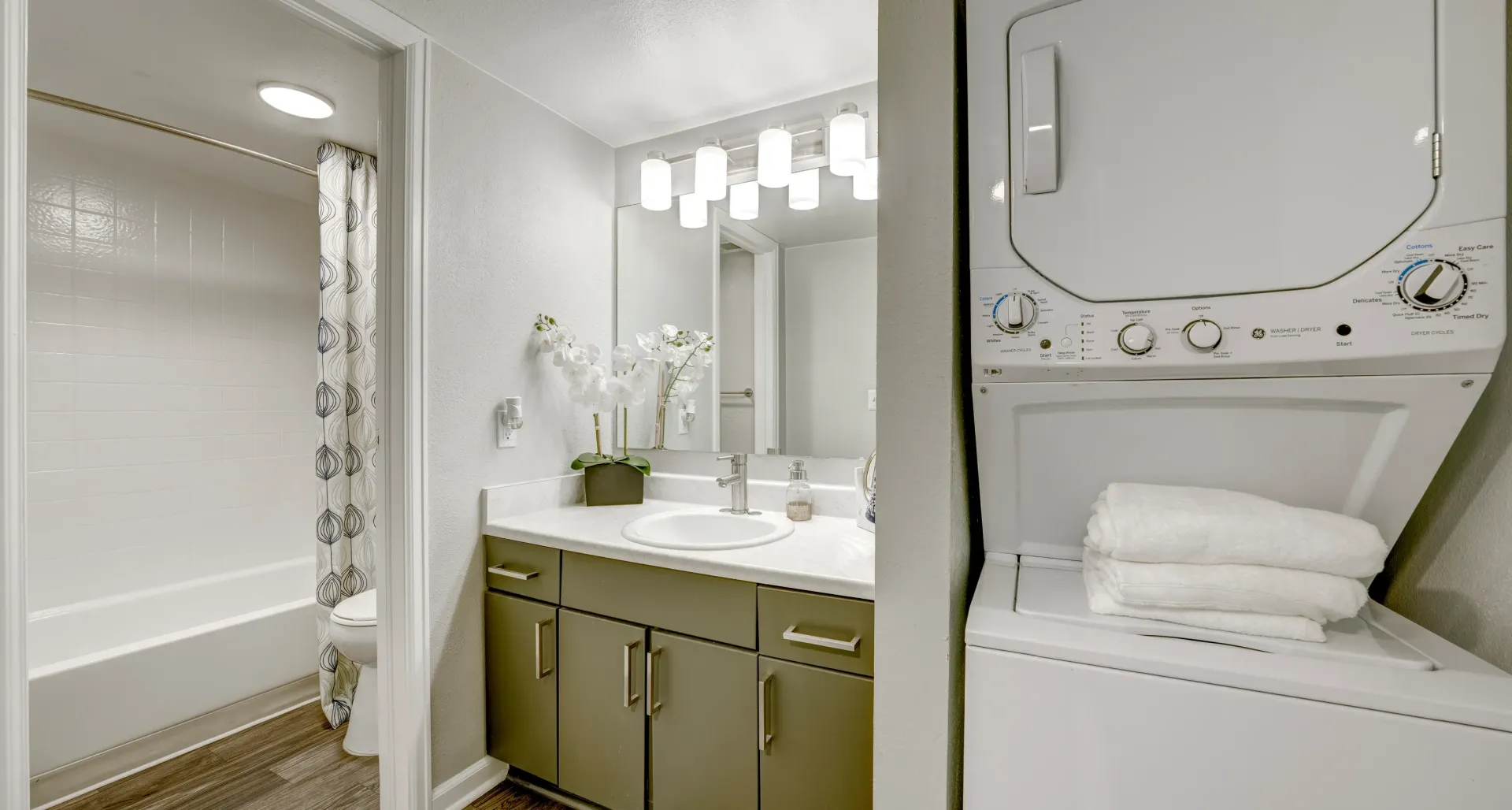 Modern bathroom with stacked washer and dryer, vanity, and bathtub.
