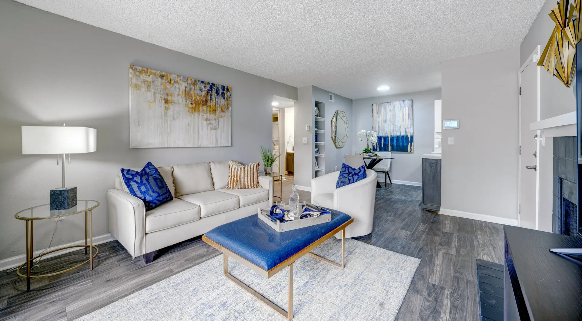 Modern living room with a couch, armchair, coffee table, and abstract art.
