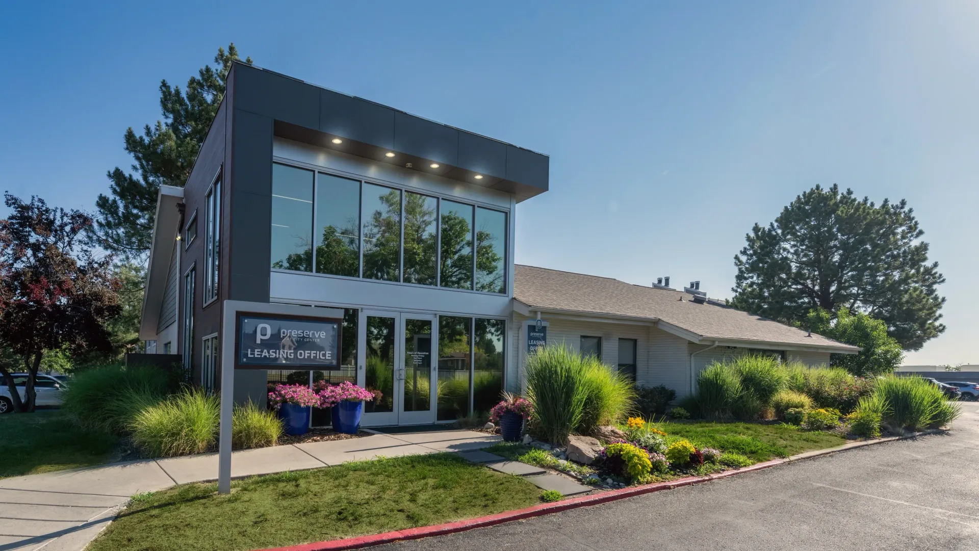 Modern leasing office building with landscaping and signage.