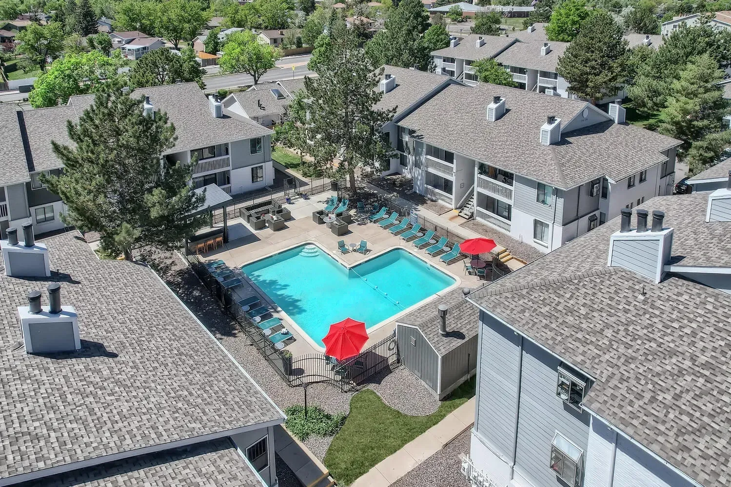 Apartment complex with a swimming pool and lounge chairs.