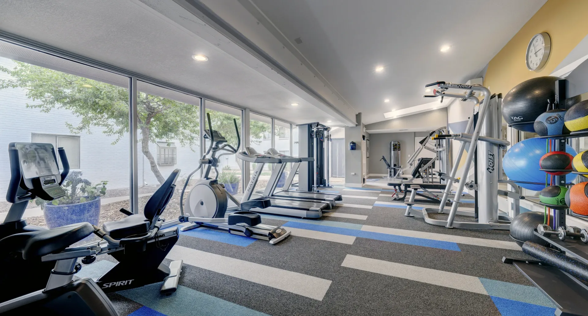 Fitness center with treadmills, ellipticals, weight machines, and medicine balls.