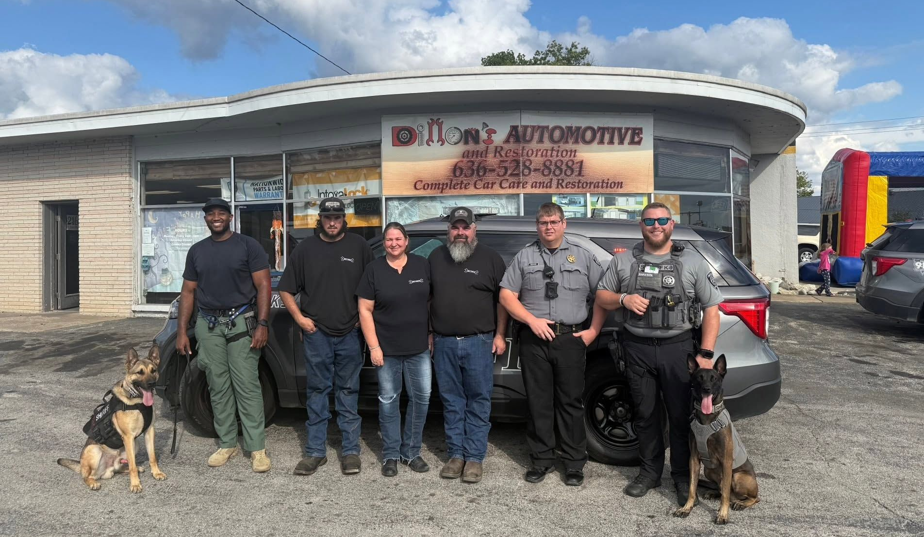 Six mechanics posing outside an auto shop with two dogs and a tow truck in the background | Dillon's Automotive