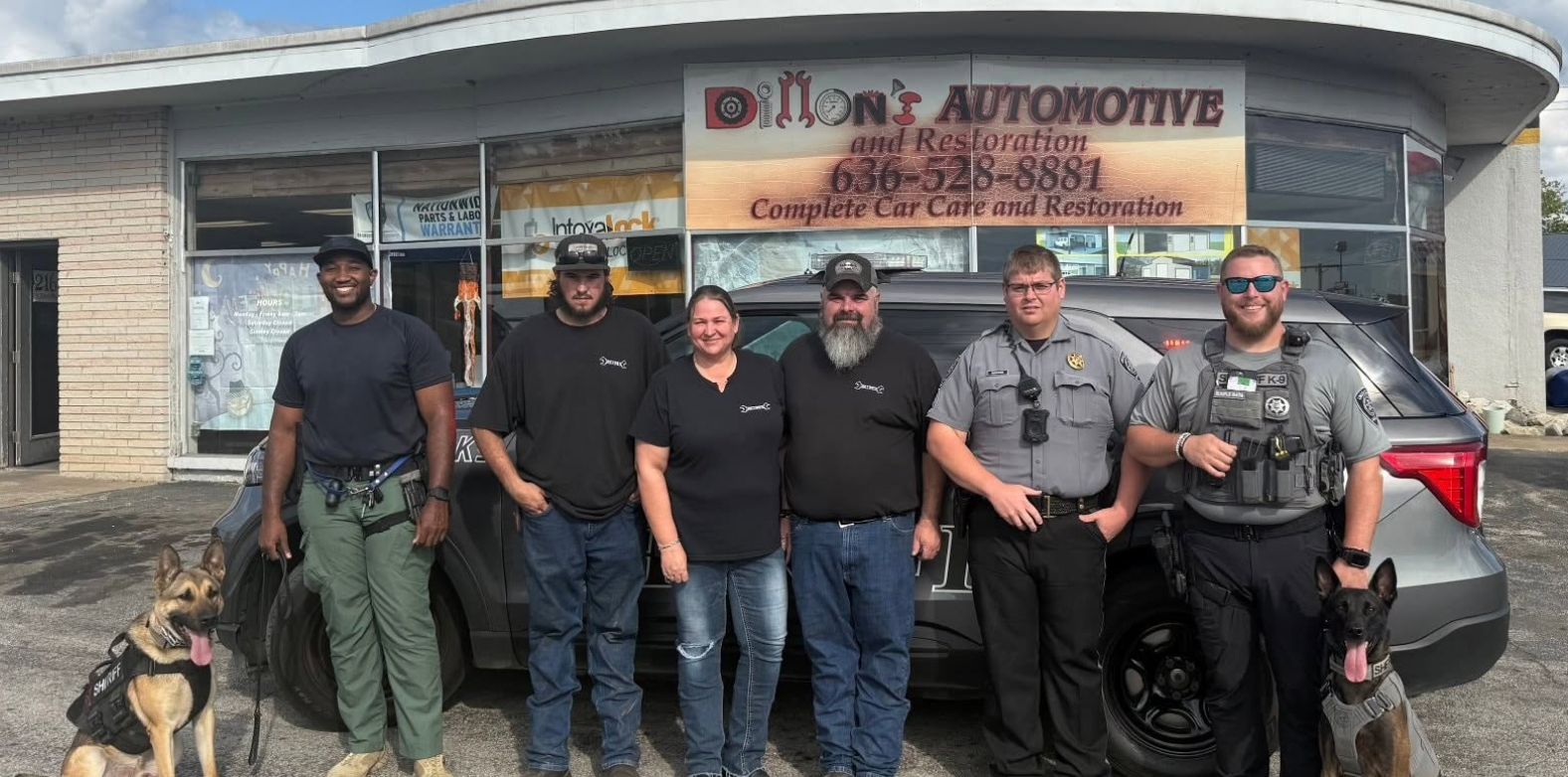 Six mechanics posing outside an auto shop with two dogs and a tow truck in the background | Dillon's Automotive