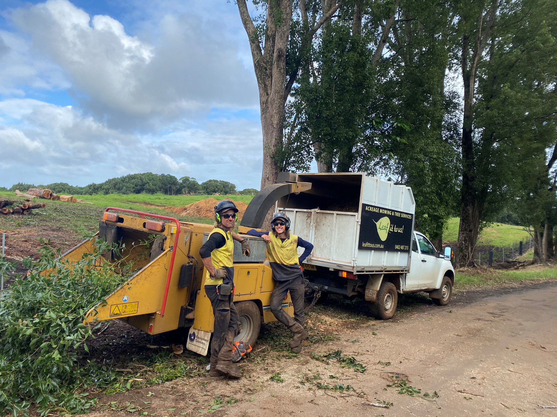Two People in Safety Gear Next to A Wood Chipper and Truck — AAA Trees On Tweed in Byron Bay, NSW