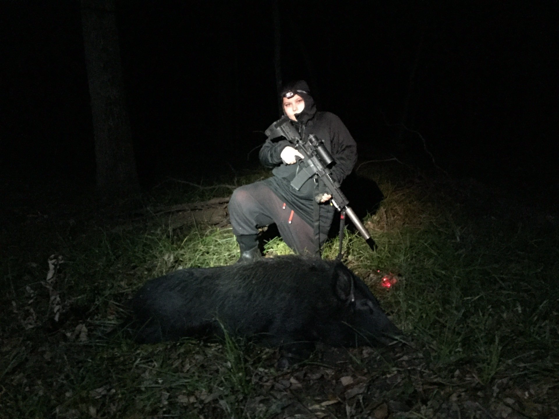 Thermal hog hunt Texas, suppressed rifle beside a black wild boar taken at night