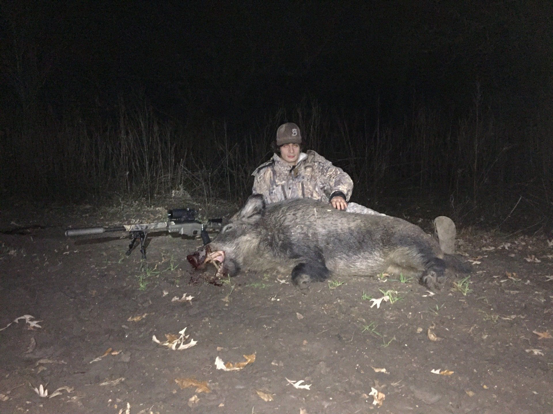 Camouflaged hunter with wild hog taken on a guided thermal hunt in the Trinity River bottom