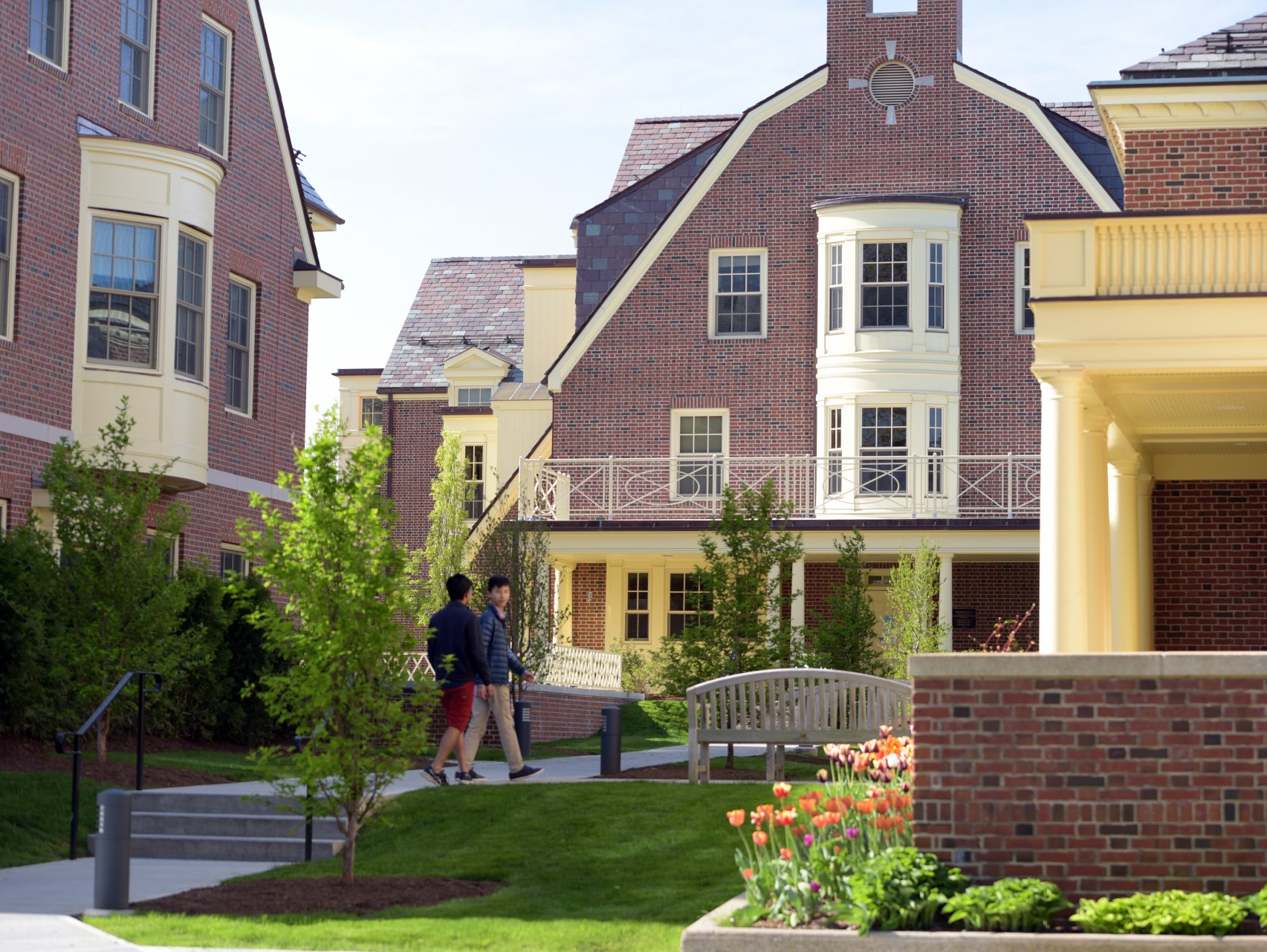 A couple of people walking in front of a brick building