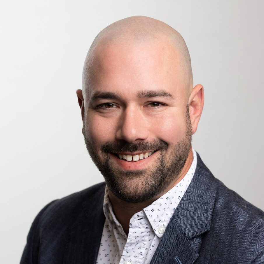 A bald man with a beard is smiling for the camera.