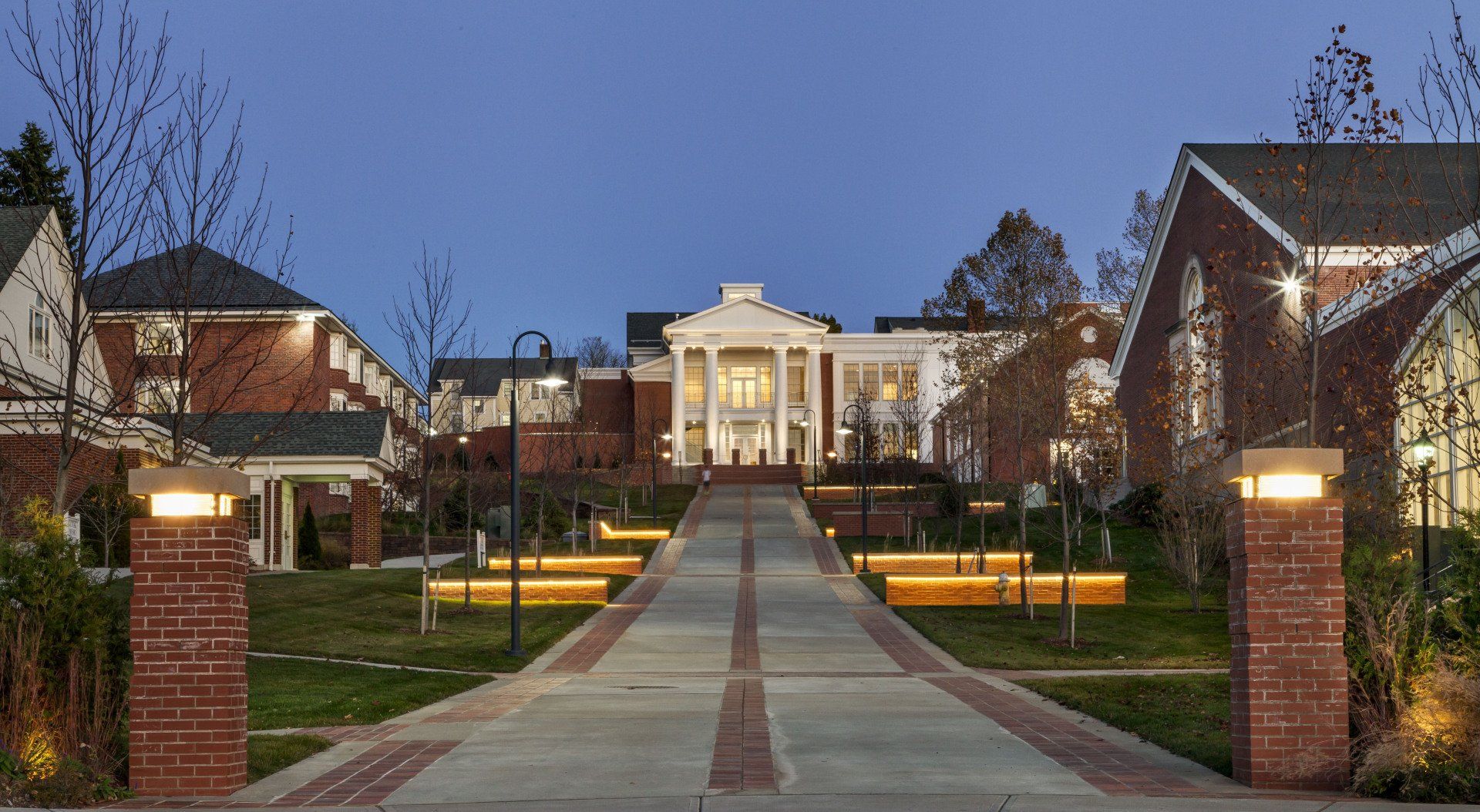 A brick driveway leading to a large white house