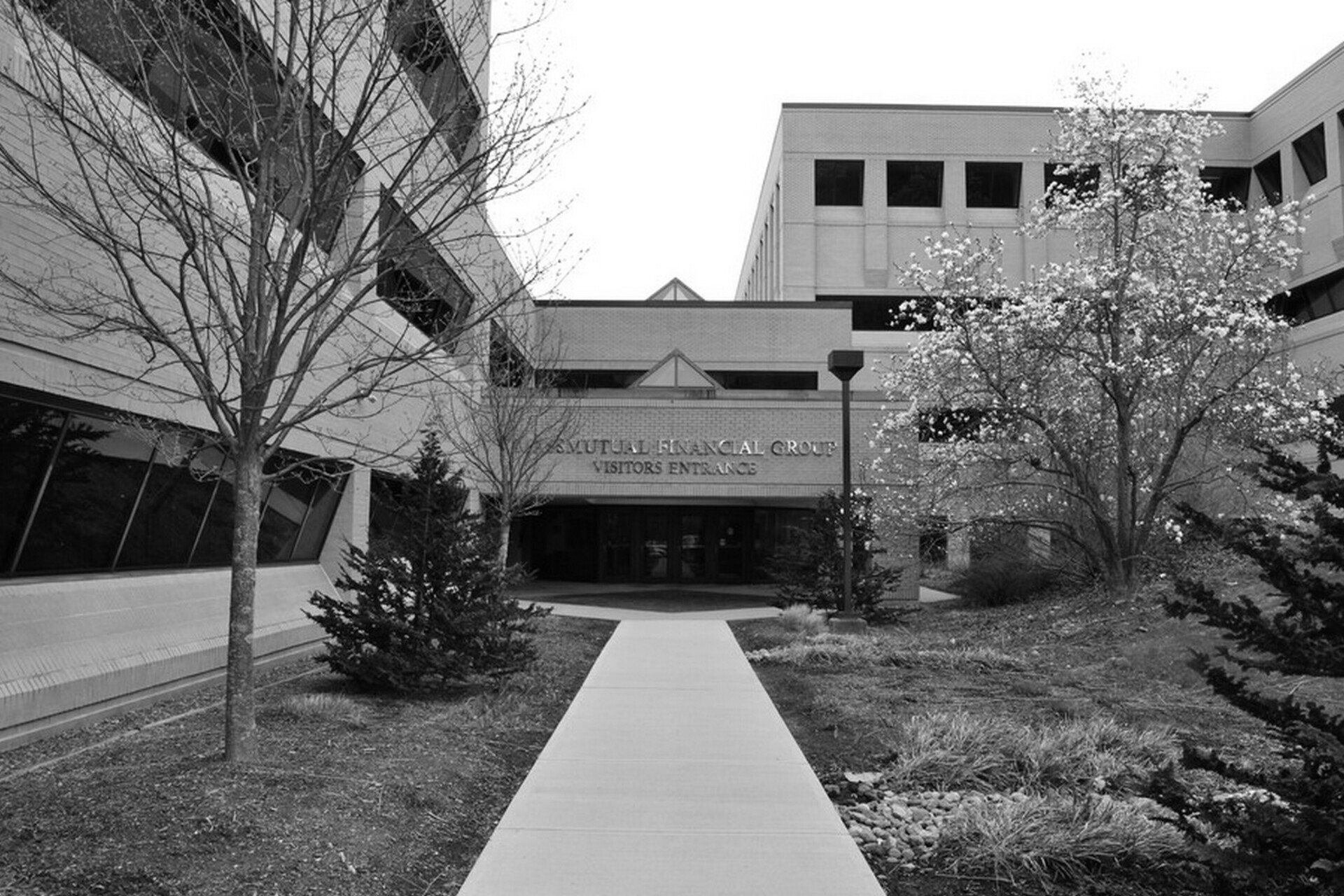 A black and white photo of a building with a walkway leading to it.