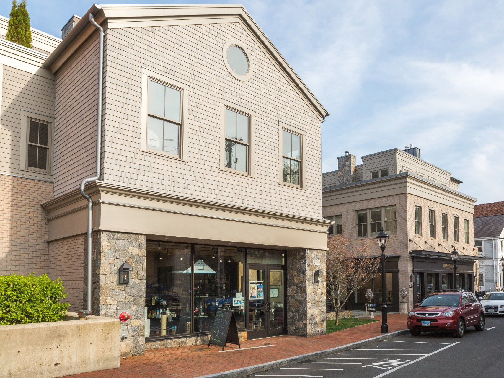 A red car is parked in front of a brick building