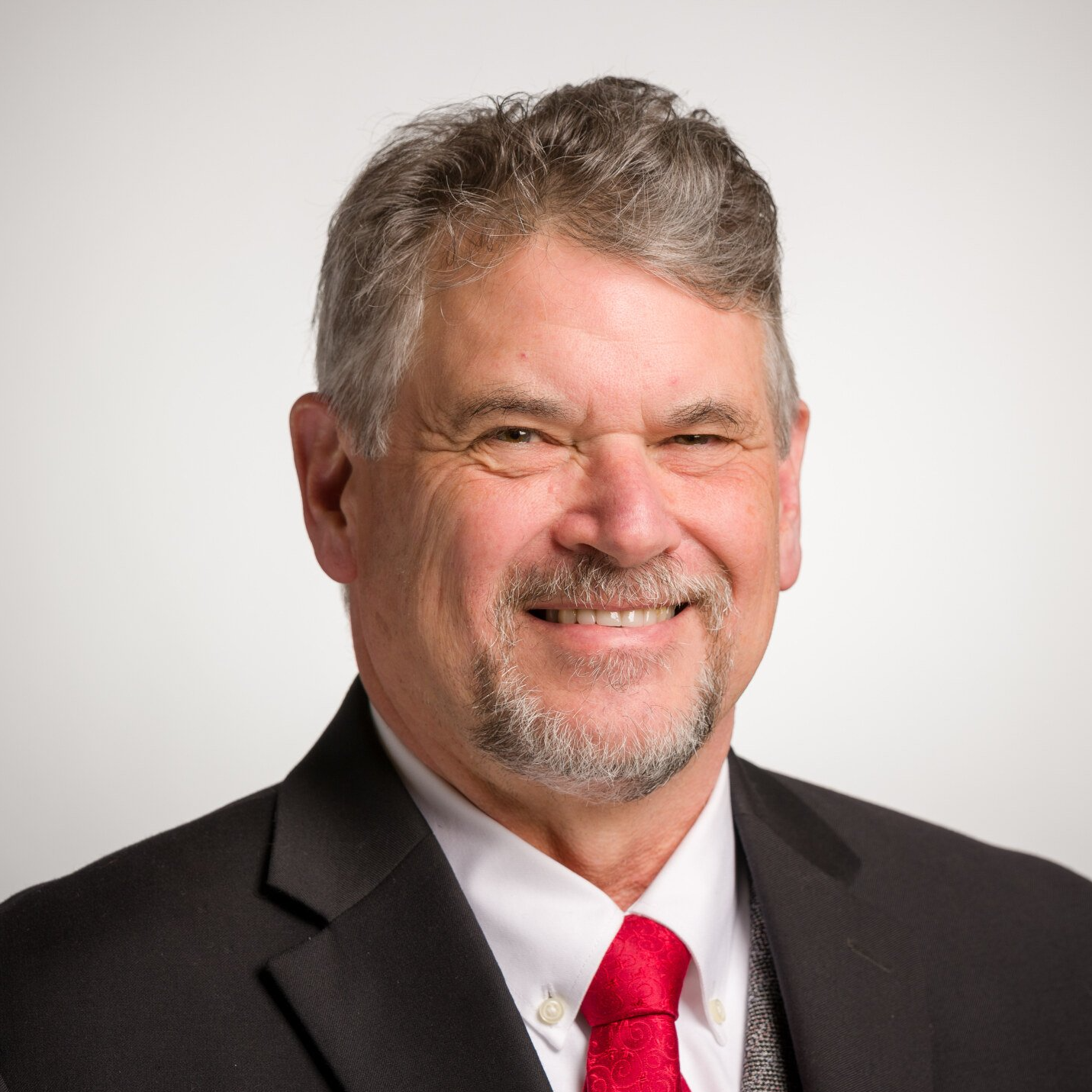 A man in a suit and tie is smiling for the camera.