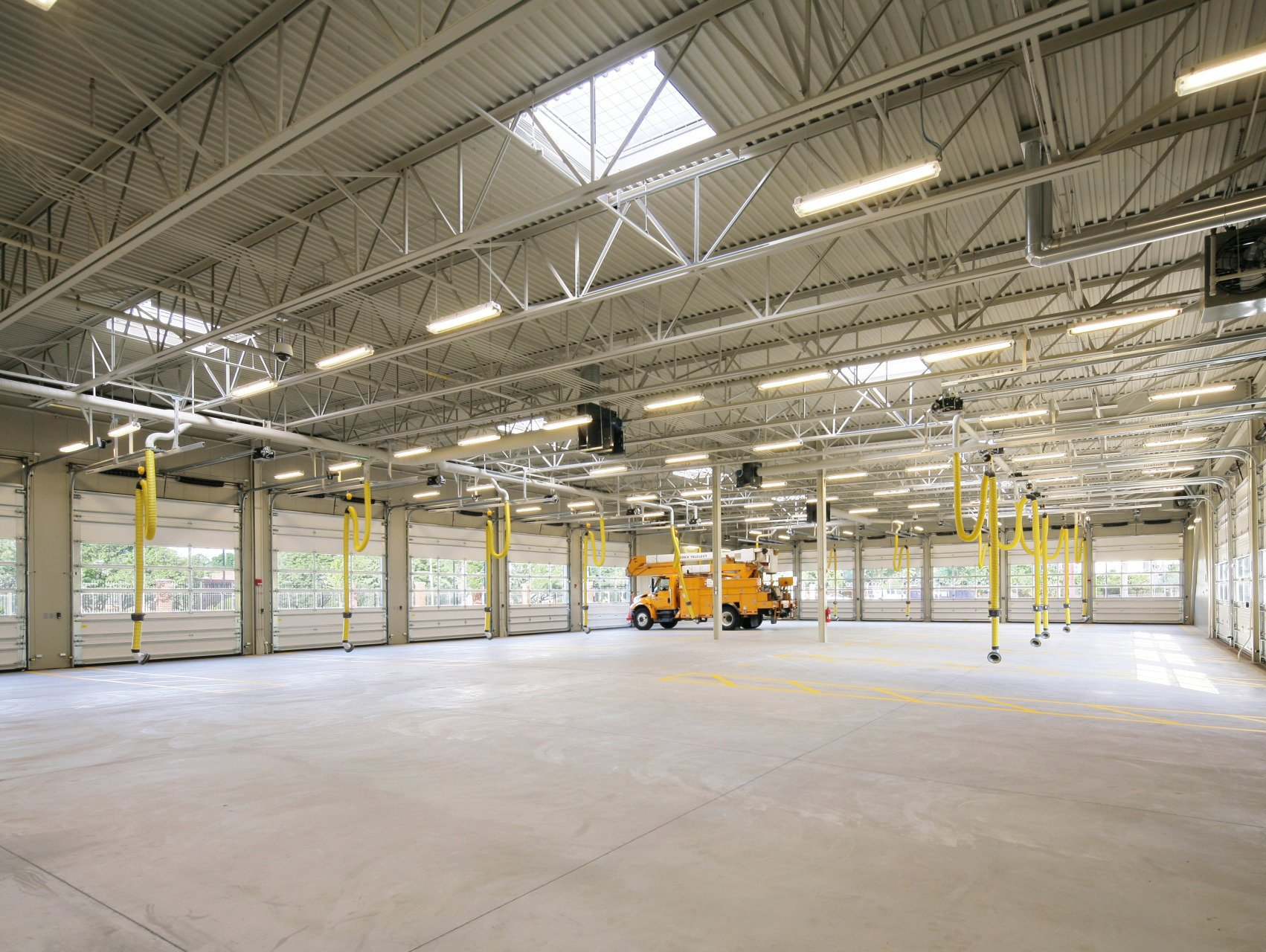 A large empty warehouse with a yellow truck parked in the middle.