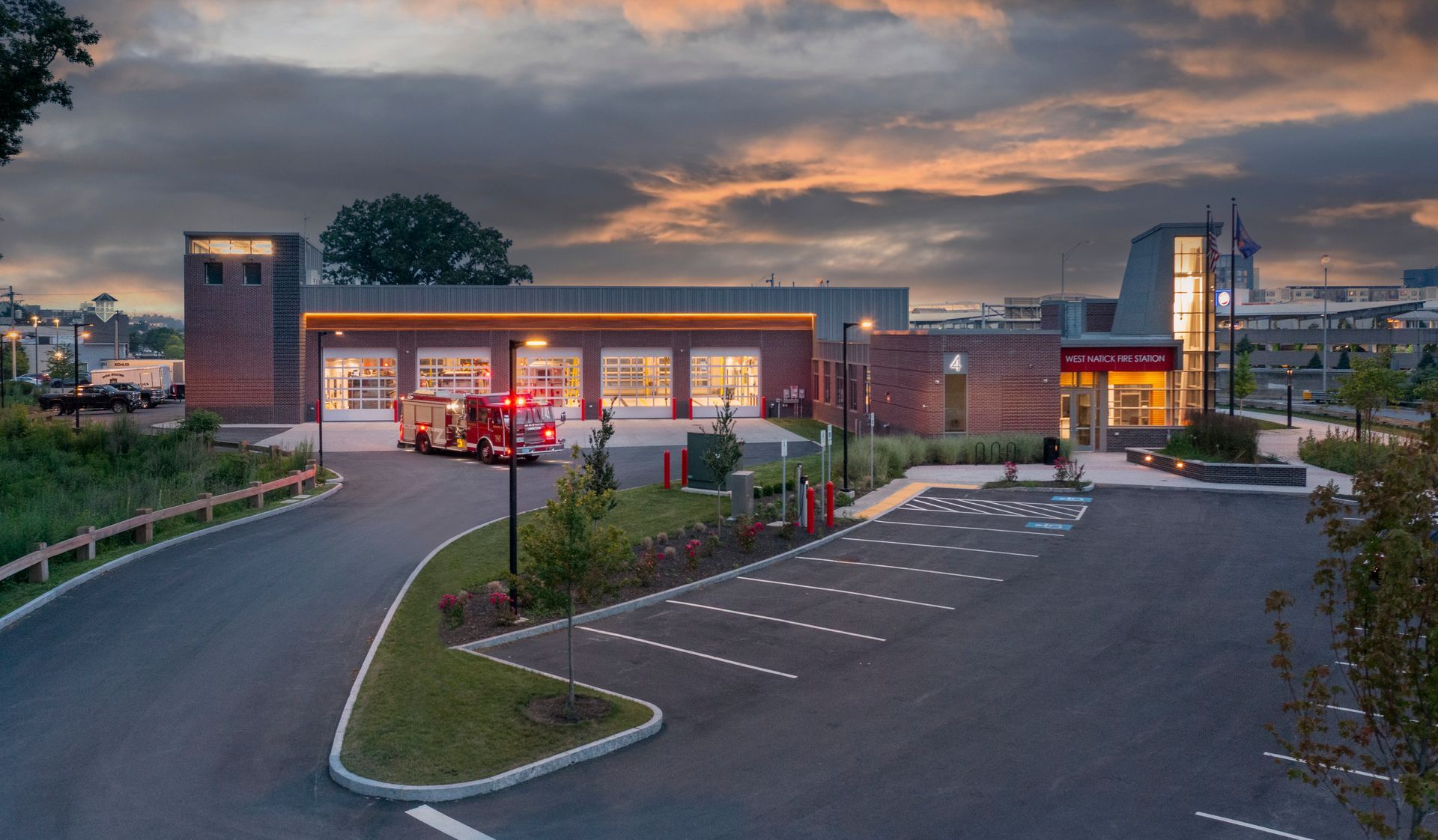 An ambulance is parked in front of a fire station at night.