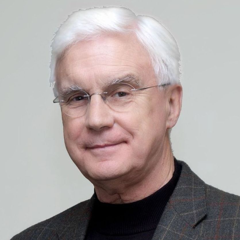A man wearing glasses and a suit is smiling for the camera.